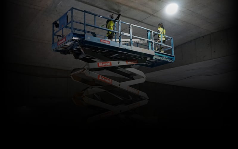 Workers on a platform lift inspect systems in the ceiling of a tunnel