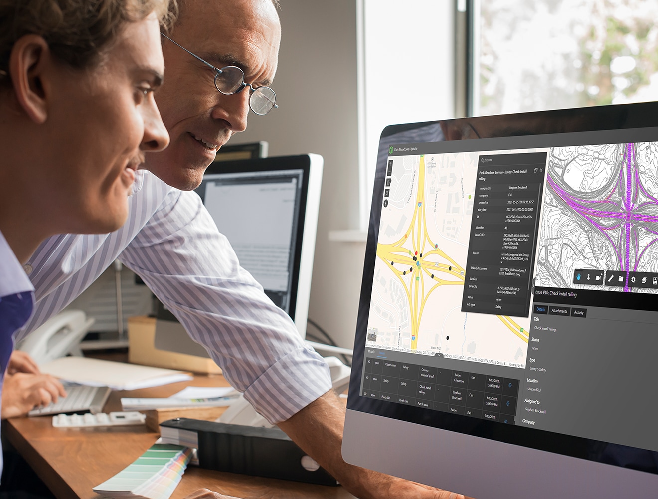 Two people collaborating on road project on computer