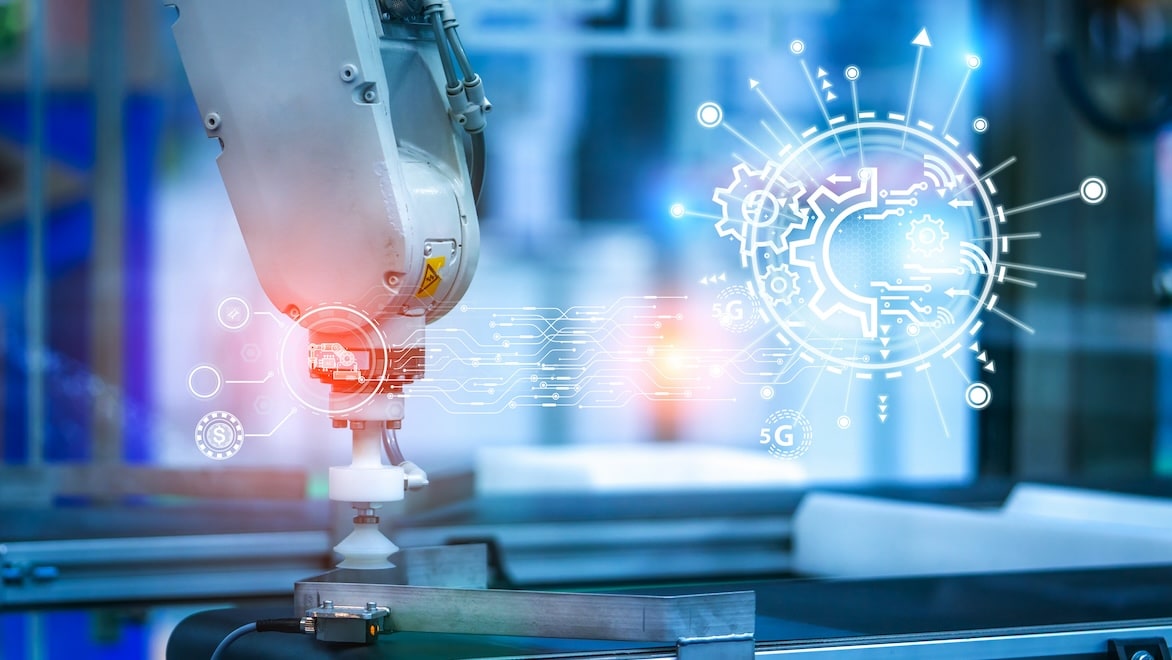 A robotic hand controlling manufacturing processes in a factory is overlaid with diagrams representing AI and machine learning.