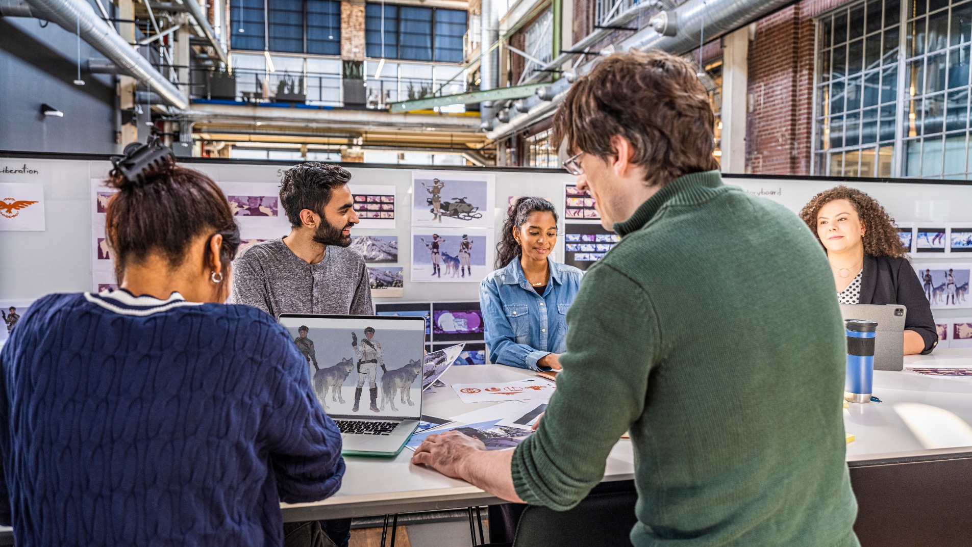 Employees collaborate around a table with project materials during a team discussion.