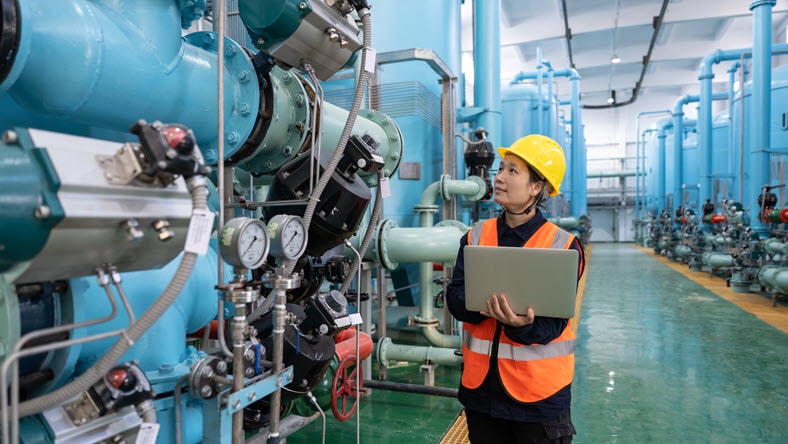 A female engineer works in a chemical plant using a laptop computer 