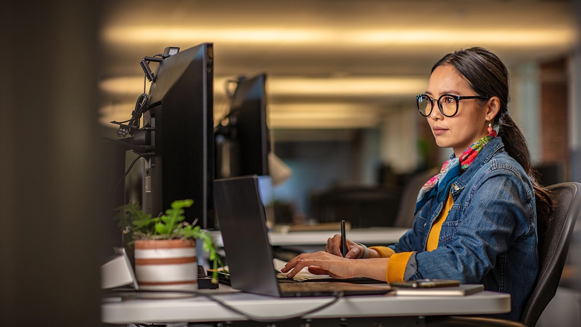 Frau sitzt am Schreibtisch und arbeitet am PC