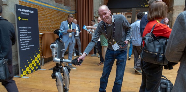 A male Autodesk employee interacts with Otto the robot.  