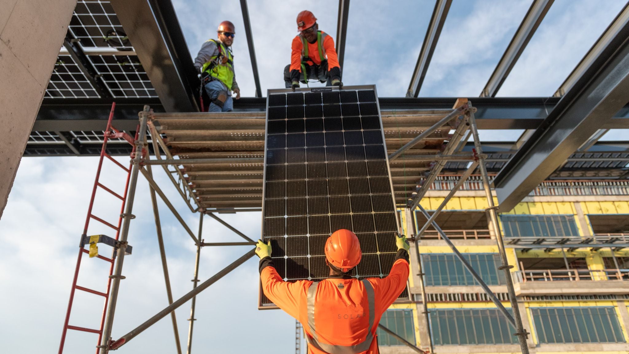 Construction workers installing a solar panel on-site as part of sustainable building practices.