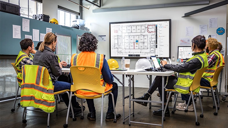 construction workers around a table viewing a floorplan