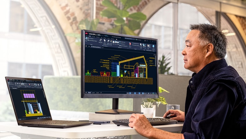 デスクトップモニターを使ってAutoCADの設計ファイルに取り組んでいる男性