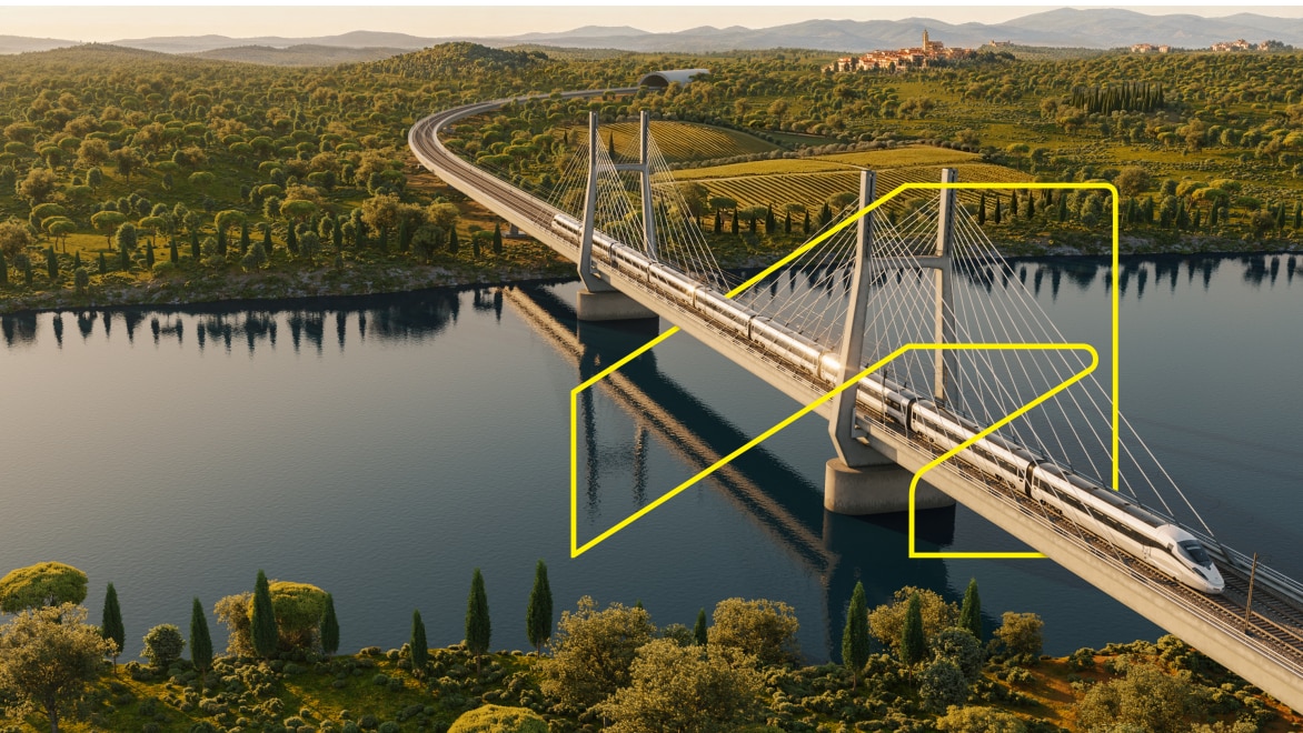 A train runs over a bridge crossing a large river. Mountains and a beautiful green landscape are visible in the background.