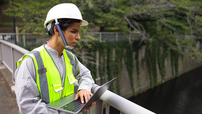 A water utility worker surveys a wastewater treatment plant with a tablet.