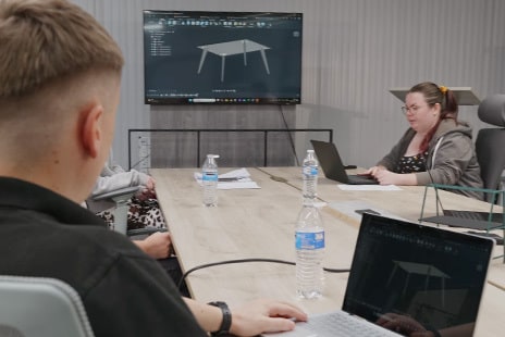 Engineers collaborating at a conference room table, reviewing a design of a table