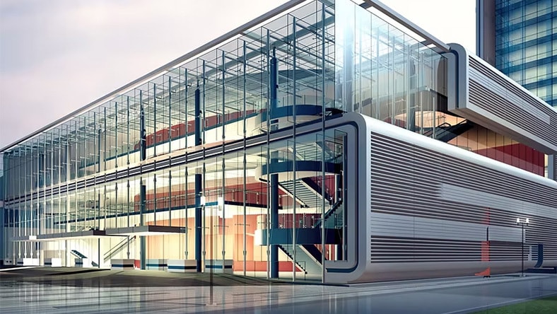 A large, modern building with a glass facade and visible interior staircases, featuring sleek architectural design and multiple floors.