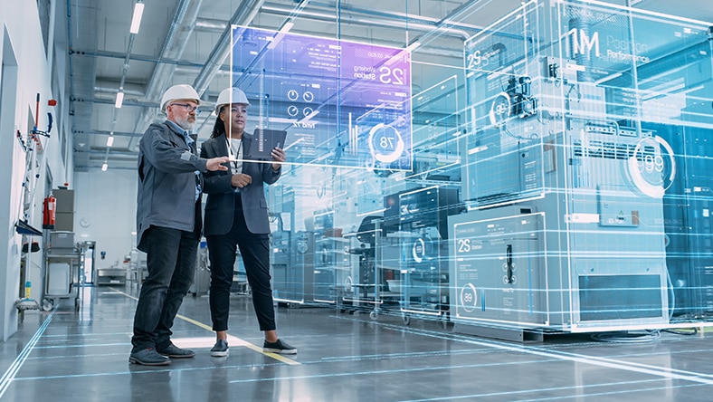 Two people wearing hard hats stand in a large industrial space interacting with transparent digital interface panels showing technical data