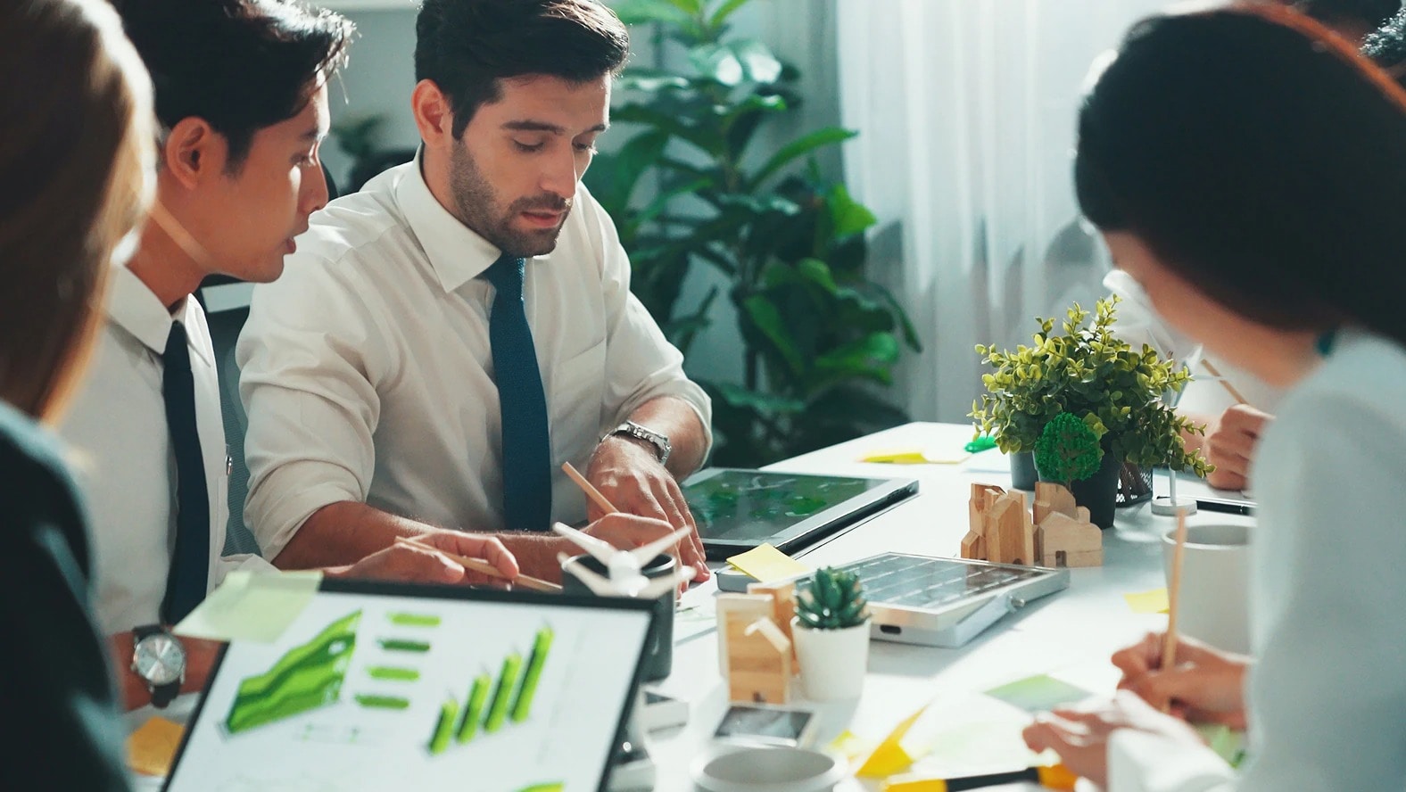 Two engineering professionals reviewing a custom window frame on a manufacturing floor while using a tablet to discuss production and quality processes.