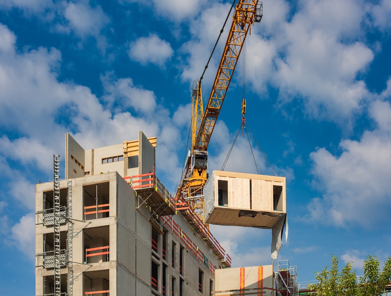 A crane moved a module of a prefabricated wooden office building into place.