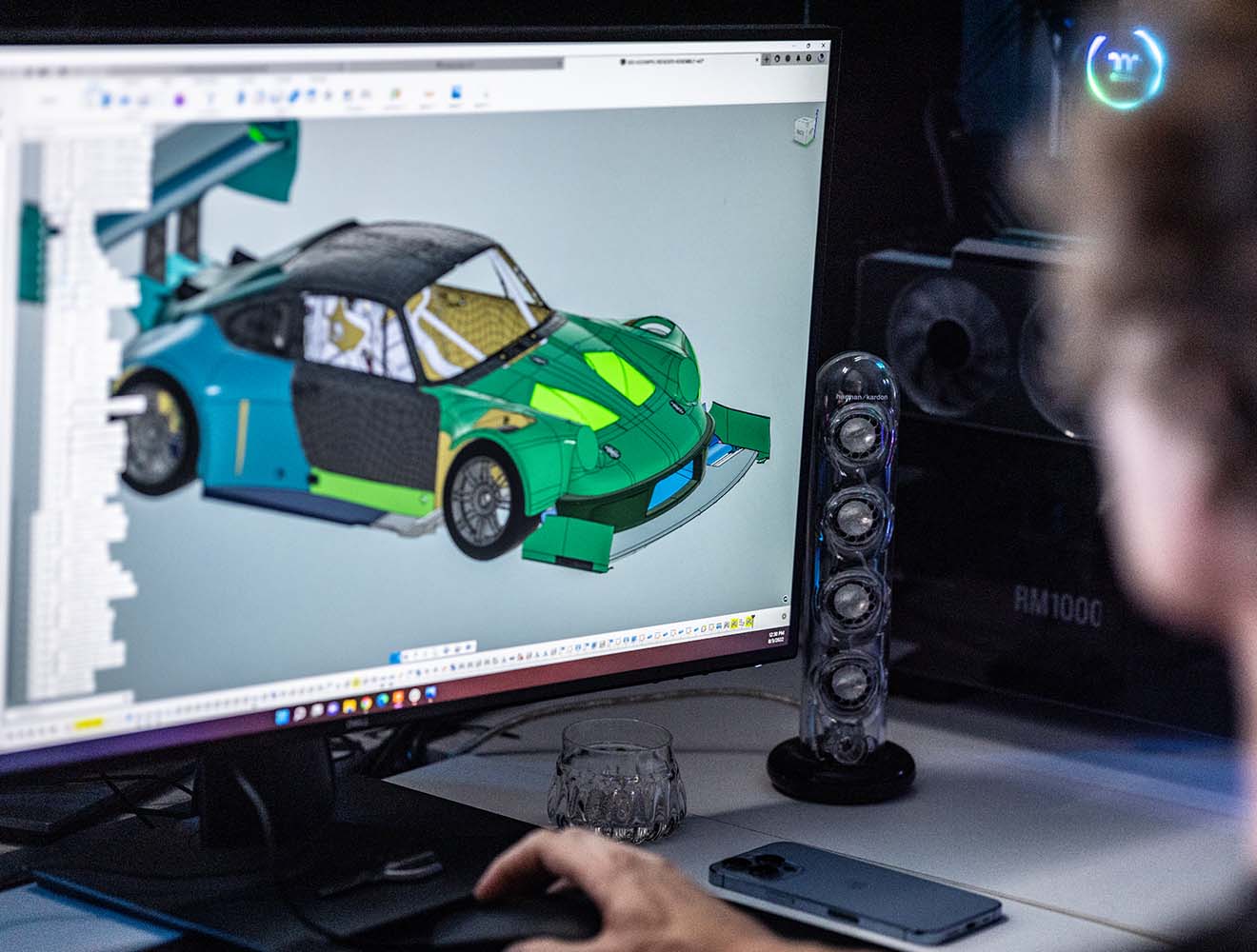 Person working on a computer, designing a 3D model of a car.