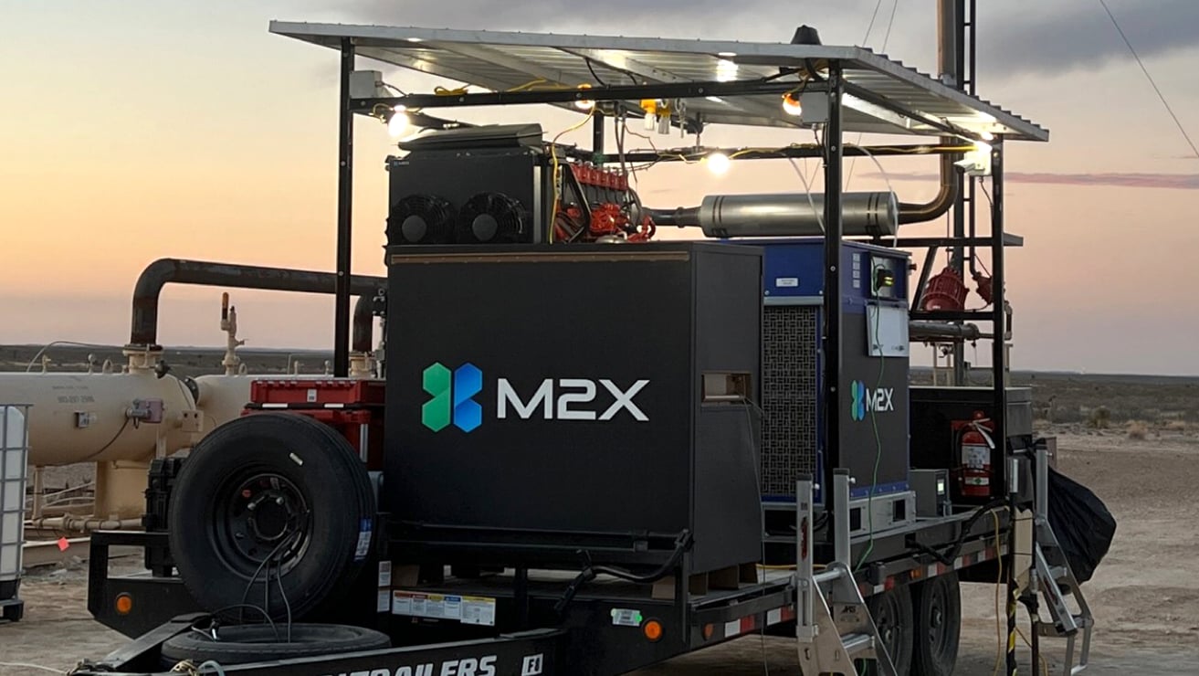 M2X Energy methane-to-methanol conversion unit in a field with a sunset in the background.