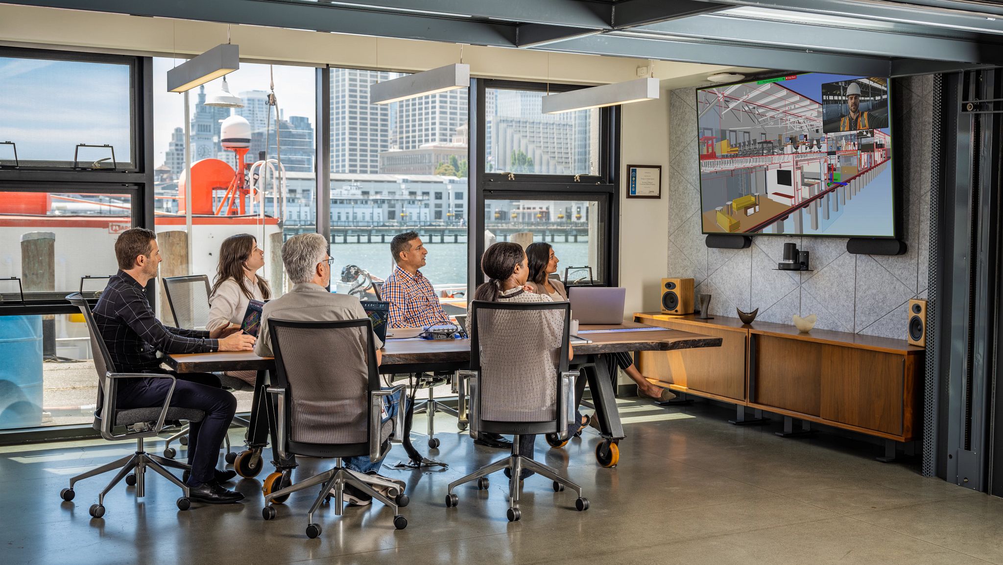 Team collaborating in a modern office, reviewing a 3D architectural model on screen discussing sustainable design.