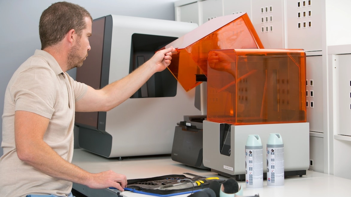 A man lifts the lid of a stereolithography 3D printer.