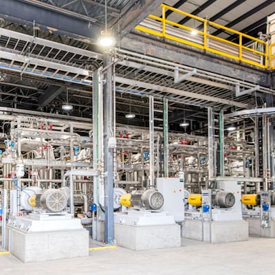 Ground level view inside the Via Separations facility—a large room roughly two stories tall with metal scaffolding, catwalks on the 2nd level, and machinery (pipes, containers, fans, etc.).