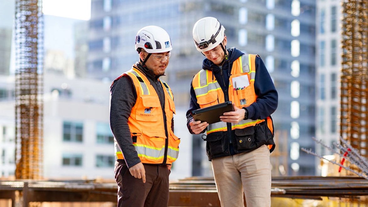 Construction team reviewing project plans on tablet onsite.