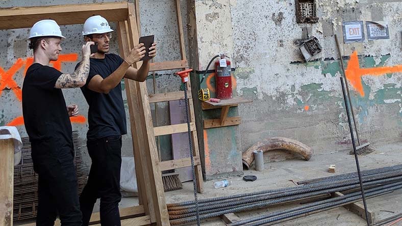 Two men use tablet on construction site.