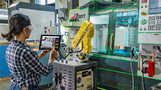 Engineer using a tablet to inspect robotic machining equipment with augmented reality overlays in a factory.