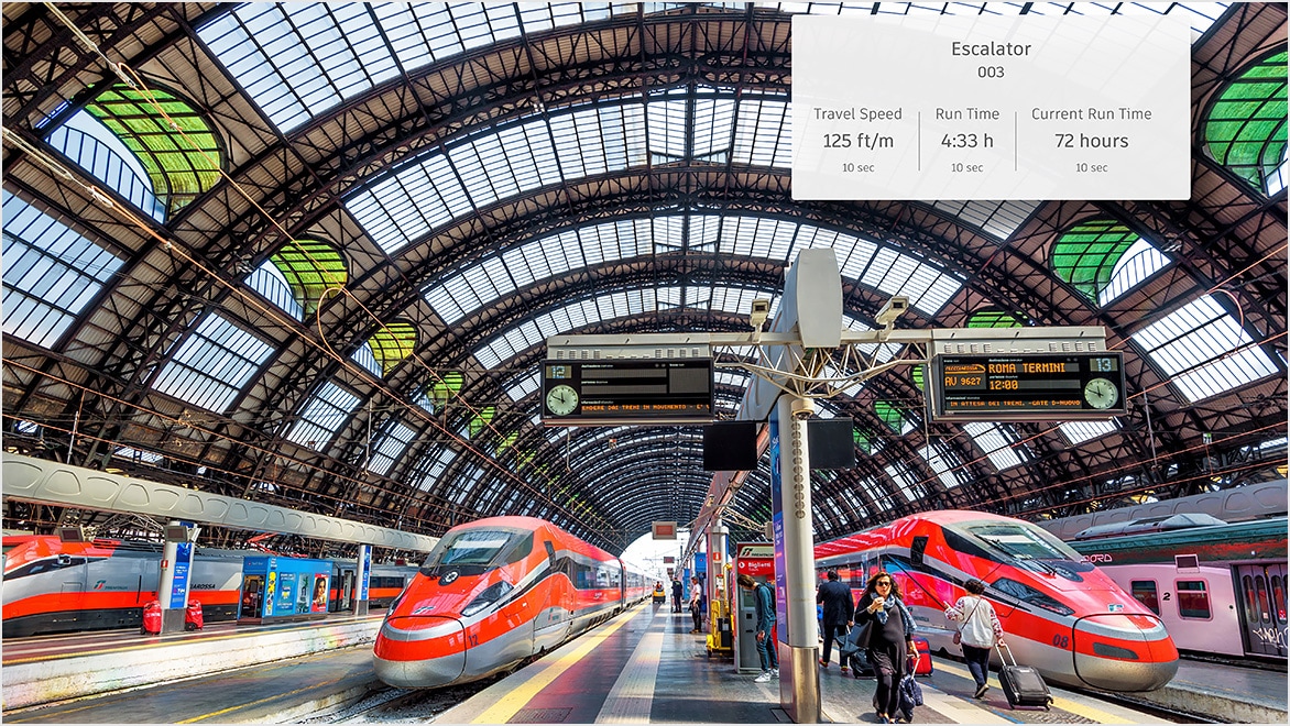 High-speed trains at a busy station with digital transit monitoring display.