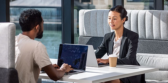 Two people sitting at a booth working together on their computers at the Autodesk San Francisco Technology Center.  