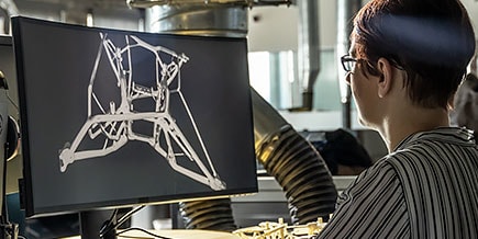 A man contemplating at his computer while viewing designs. 