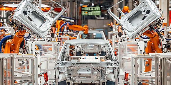 A vehicle being manufactured on a factory floor through machine automation. 