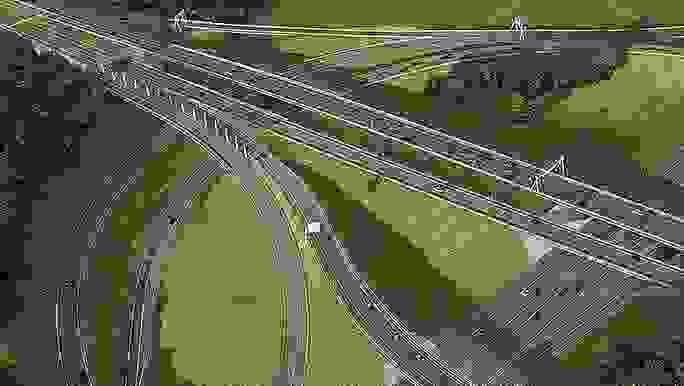 A birds-eye view of multiple connected highways and cars surrounded by green grass and trees