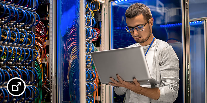 A man holding a laptop while working in a data center