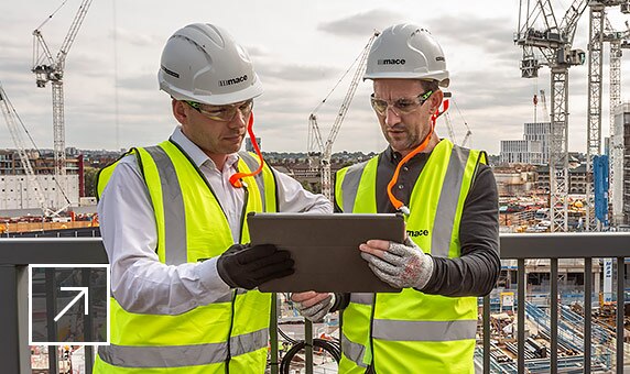 Dois homens num terreno de construção a partilhar um tablet 