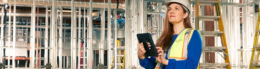 Eine Frau auf einer Baustelle greift auf einem Tablet auf ihre DWG-Dateien zu 