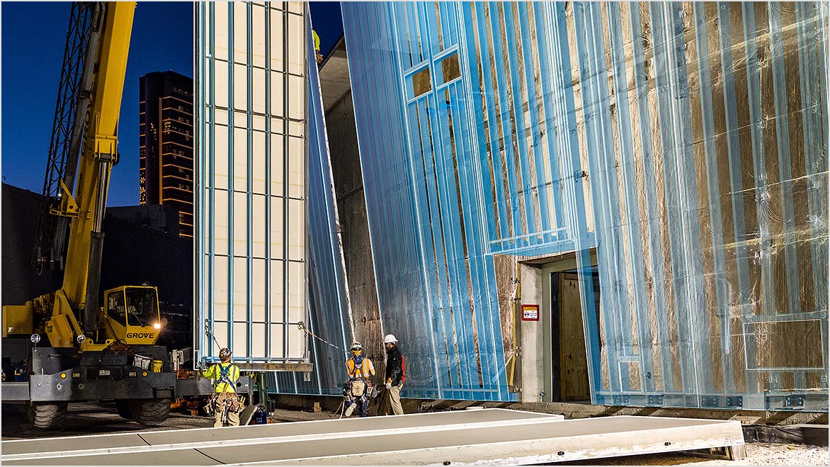 AECO professionals on a construction site with a crane adding side panels to a building.