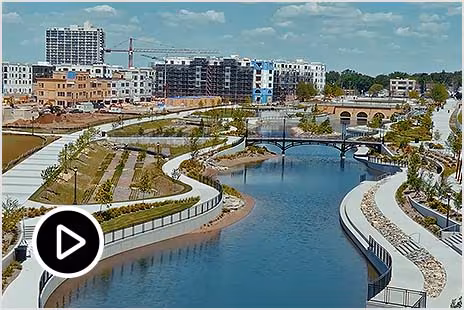 Aerial view of a river with landscaped banks and bridges in an urban area.