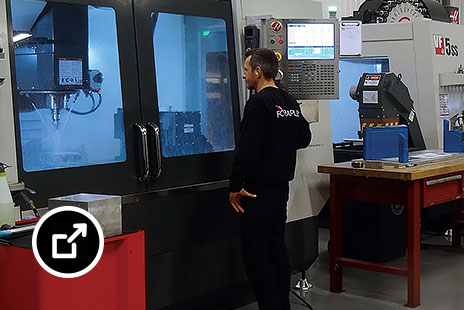 Two people working in a factory using CNC machining equipment