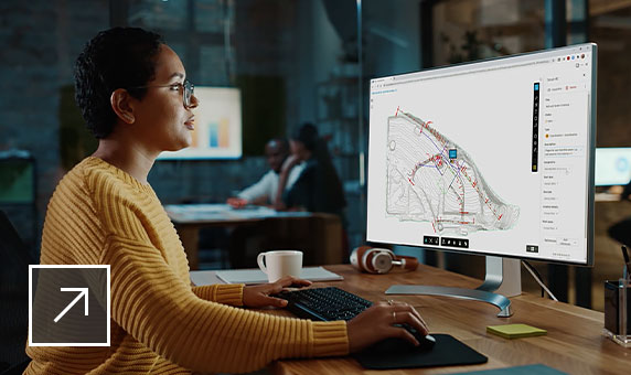 BIM Collaborate Pro ソフトウェアを使用しながら、デスクでコンピュータ画面を見ている女性。