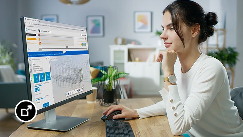 Vrouw die aan een bureau zit en op haar computerscherm kijkt terwijl ze BIM Collaboration-software gebruikt