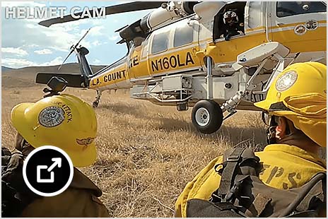 Helmet Cam footage shows three first responders in yellow in front of a helicopter