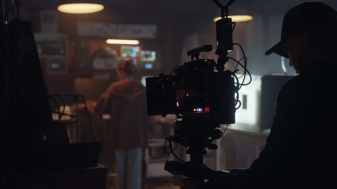 摄影机背后的男人拍摄黑暗场景中的演员 