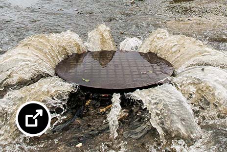 Water and sewage spilling from a sewer pipe in the middle of a residential street