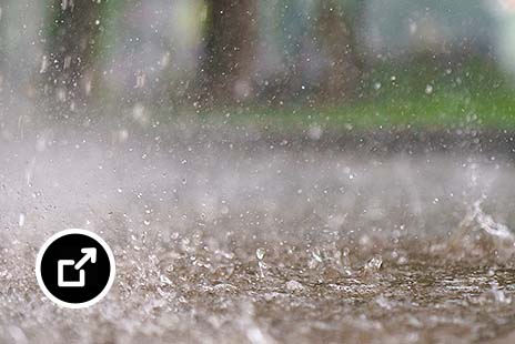 Rain falling on a cement street causing light flooding