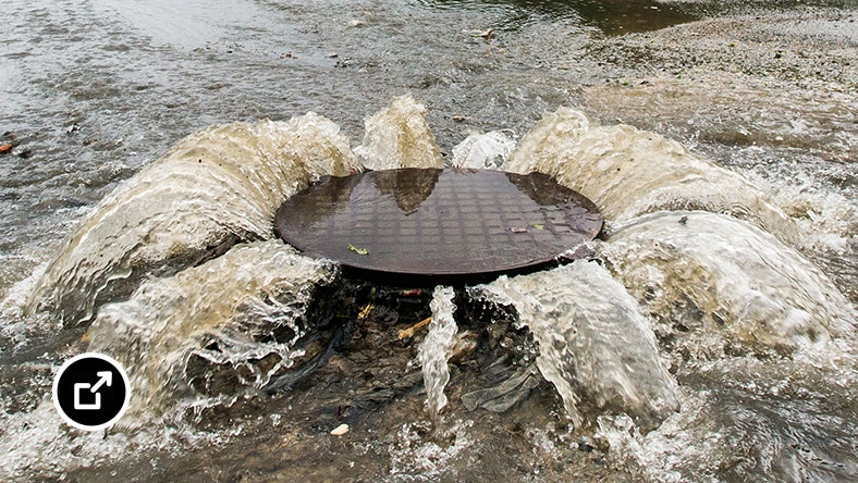 Overflowing sewer in a flooded area.