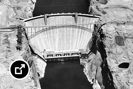 Vista aérea a preto-e-branco de uma barragem de betão armado construída num desfiladeiro de pedra