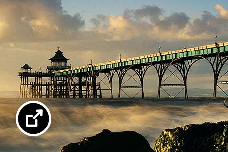 Pier extending into the sea with ornate pavilions and a wooden walkway 