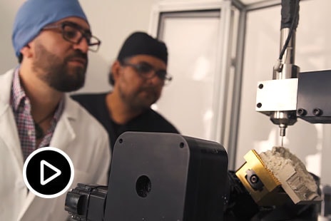 Zwei Männer prüfen, wie eine Maschine ein Schädelimplantat fertigt 