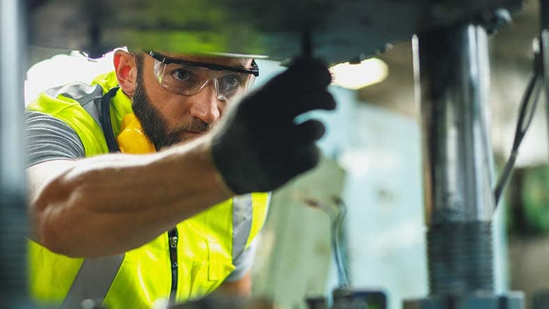 Image showing a worker maintaining a machine according to maintenance schedules in Autodesk Fusion Operations.