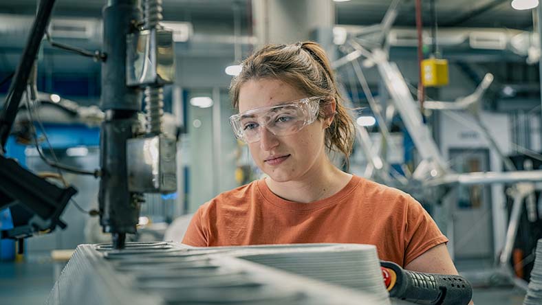 Image showing a worker in a manufacturing facility identifying what workflows to use for creating a product using Autodesk Fusion Operations.