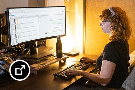 Melissa Gray sentada en su escritorio con el software ShotGrid en el monitor