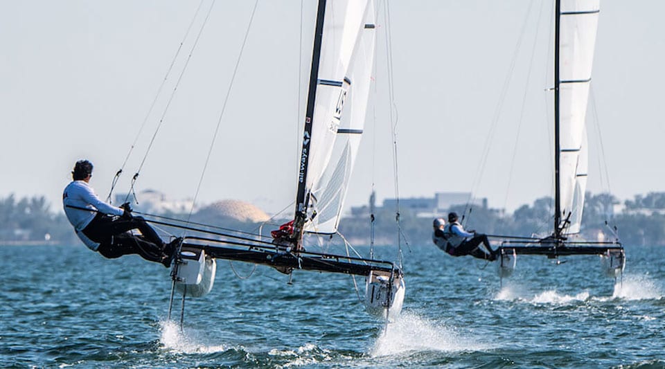 US Sailing team members sailing on the water on 2 hydrofoiling dinghies